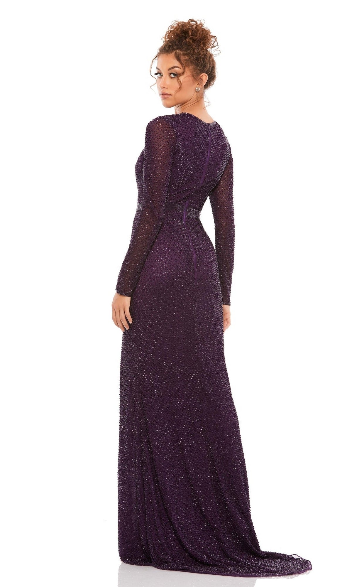 A woman with curly hair poses in the Long Formal Dress 5056 by Mac Duggal—a floor-length, dark purple gown with subtle shimmer—against a plain white background.